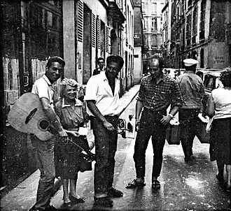 alt=Robin Page en Peter Golding als straatmuzikanten naast de eigenaresse van The Beat Hotel, eind
jaren '50