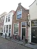 Huis met puntgevel met in het zoldervenster roedenverdeling in stijl
