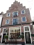 Huis met hoge trapgevel met ezelsruggen bovendeel gerestaureerd