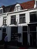 Huis onder een hoog zadeldak met het nr 26