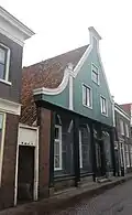 Huis met aan de straat een houten puntgevel met zijpilasters en links een ingezwenkt vleugelstuk