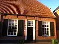 Gaaf bewaard rechter gedeelte van een door een dwars wolfdak gedekt dorpshuis op bentheimer plint