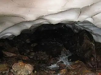 De Riu de l'Estany baant zich een weg onder een smeltende ijskap op het traject tussen de meertjes Estany Negre en Basses de l'Estany Negre