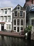 Gaaf huisje op de hoek van de Vijgensteeg. De lijstgevel heeft een hoge, houten pui met insteekverdieping en met gesneden festoenversieringen
