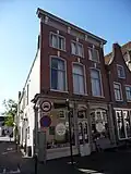 Lunchroom met woonhuis op verdieping, voorm. winkel/woonhuis in invloeden neorenaissance