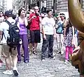 Mensen maken een foto terwijl iemand over Charging Bull wrijft. Ook het scrotum van de bronzen stier in New York glanst door de vele aanrakingen.