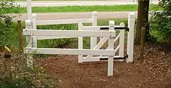 Slingerhek bij een bospad. Door het draaibare deurtje kunnen rolstoelen wel, maar fietsen niet passeren.