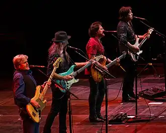 The Doobie Brothers tijdens een optreden in 2017. V.l.n.r. tourbassist John Cowan, Patrick Simmons, Tom Johnston en John McFee.