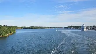 De baai gezien in noordelijke richting. Ter hoogte van het grote schip (rechts) is net wat bebouwing van Mariehamn zichtbaar.