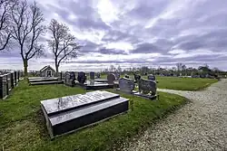 Overzicht over de begraafplaats van Thesinge met links (voorgrond) de hervormde en rechts (achtergrond) de gereformeerde graven. De gereformeerde begraafplaats werd in 1873 gesticht nadat het kerkhof voor hen gesloten werd door de hervormden omdat ze geen jaarlijkse bijdrage wilden leveren. In 1927 kochten de hervormden een perceel ernaast en werd de tussenliggende gracht gedempt, zodat ze beiden van het baarhuis gebruik konden maken.