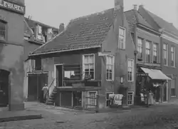 1895 (ca.): In het pand was een wagenmakerij gevestigd en in de potkast een schoenmakerij