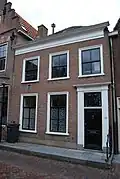 Huis met eenvoudige lijstgevel met deuromlijsting door pilasters en in de verdieping schuiframen