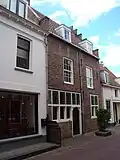 Dwarshuis met zadeldak en gepleisterde gevel met muurankers. Restanten stadsmuur.