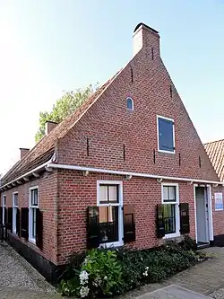 Visserswoning onder zadeldak tegen voortopgevel met moet van kleine rond gesloten lichtopening(Museum 't Fiskershúske)