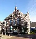 Hoekpand met twee woningen, koetshuis en winkel