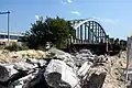 De restanten van de brug, met op de achtergrond de spoorbrug. Foto: september 2008