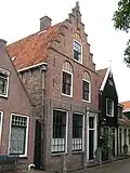 Huis met trapgevel. Pui, met gesneden deur en snijraam