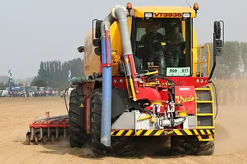 Figuur III: zelfrijdende mesttank met twee assen in hondengang en met achterop een bouwlandbemester met schijven