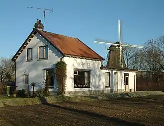 Het voormalig stationsgebouw van Wijdenes in 2003 met De Stofmolen op de achtergrond.