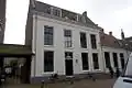 Breed gebouw met gepleisterde lijstgevel begin